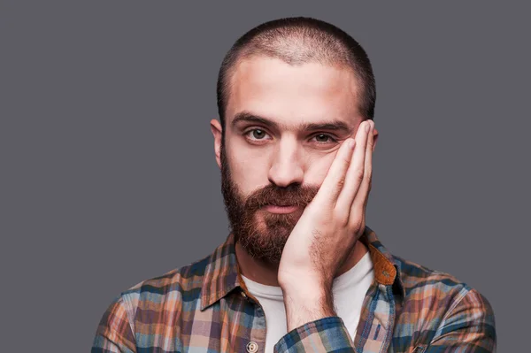 Bearded man keeping arms crossed and expressing ironic smile