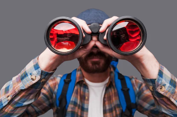 Hombre barbudo llevando mochila y mirando a través de binoculares —  Fotos de Stock