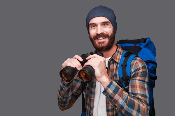 Bearded man with backpack holding binoculars — Stock Photo, Image