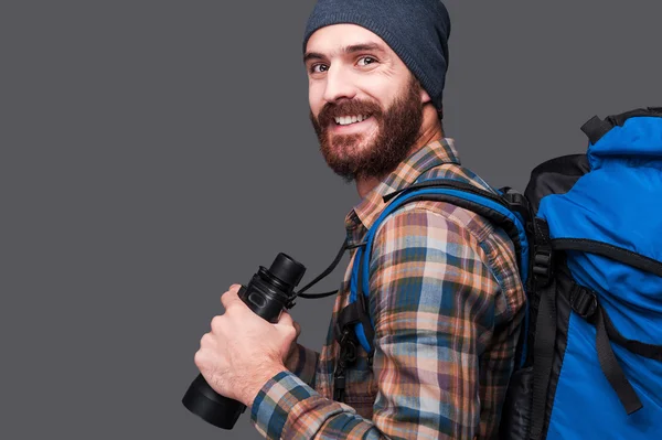 Bearded man with backpack holding binoculars — Stock Photo, Image