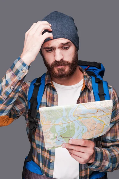 Bearded man carrying backpack and examining map