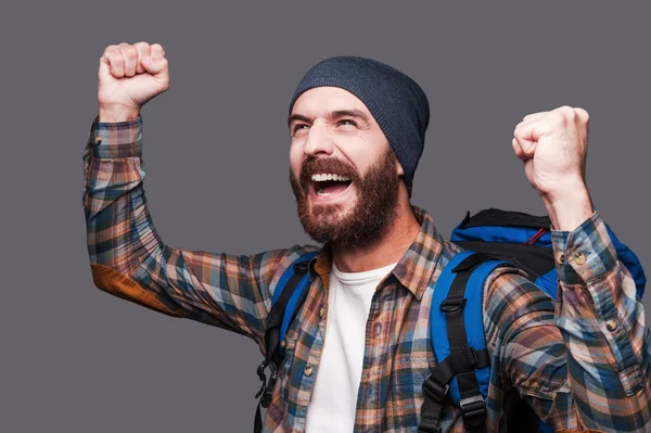 Bearded man carrying backpack and raising arms up — Stock Photo, Image