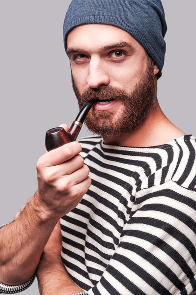 Bearded man in striped clothing smoking a pipe — Stock Photo, Image