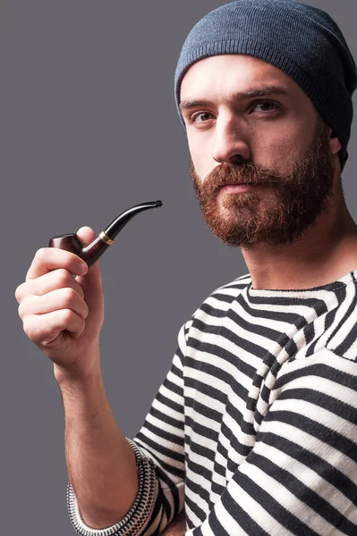 Homme barbu en vêtements rayés tenant une pipe à fumer — Photo