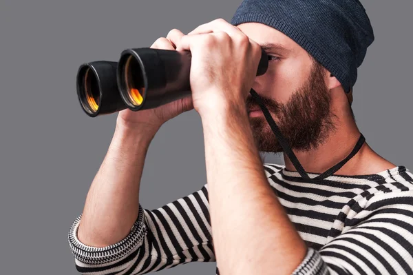 Young bearded man looking through binoculars — Stock Photo, Image