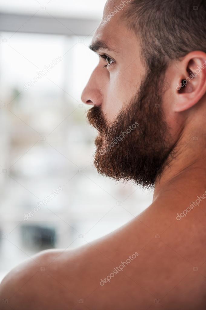 Thoughtful young bearded and shirtless man