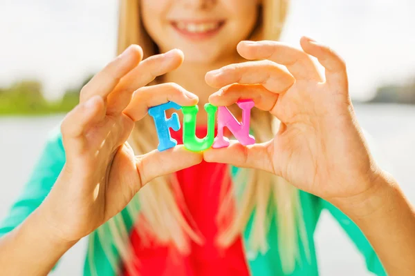 Little girl holding colorful plastic letters in hands — Stock Photo, Image