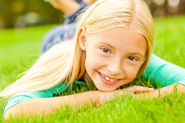 Klein meisje liggend op groen gras — Stockfoto