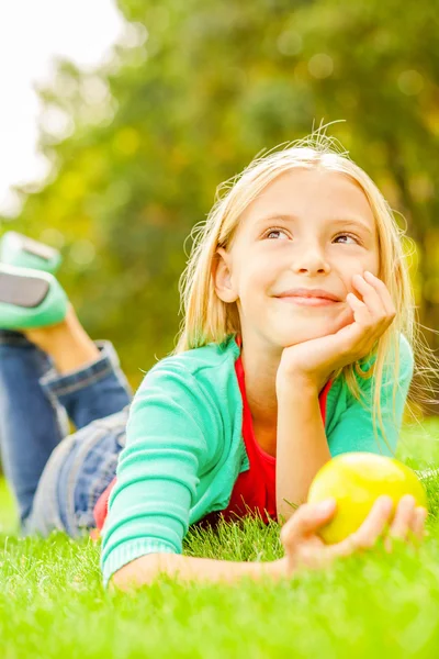 Klein meisje liggend op het groene gras — Stockfoto