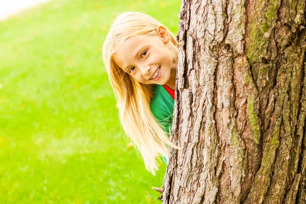 Meisje op zoek uit de boom — Stockfoto