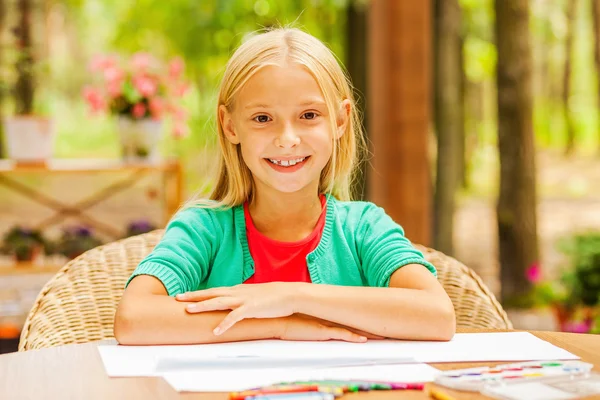 Malá dívka sedí u stolu s barevné tužky — Stock fotografie