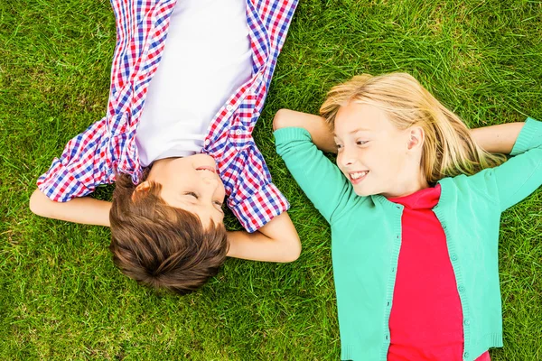 Små barn liggande på det gröna gräset — Stockfoto