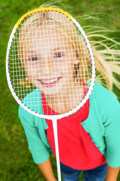 她的脸庞背后羽毛球拍的小女孩 — 图库照片
