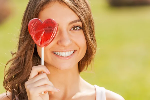 Woman holding lollipop in front of eye — Stock Photo, Image