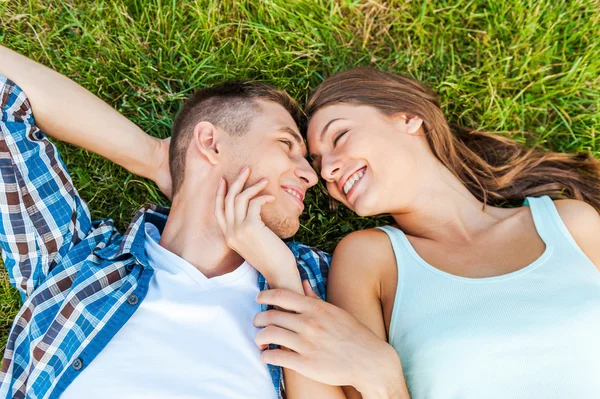 Unga par som ligger på gräset — Stockfoto