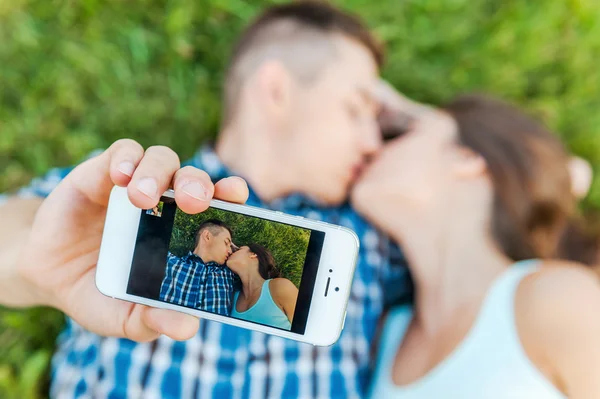 Любящая пара делает селфи и целуется — стоковое фото