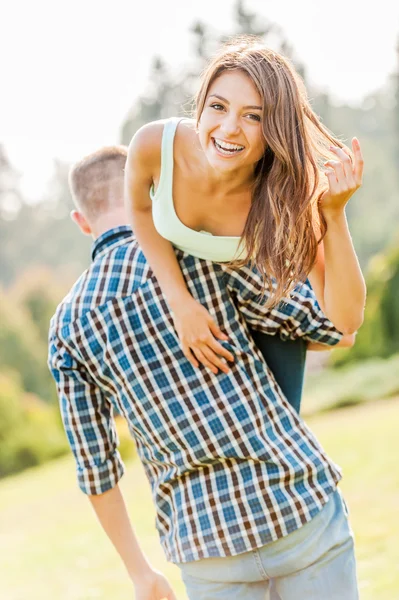 Uomo tenendo bella ragazza allegra sulla spalla — Foto Stock