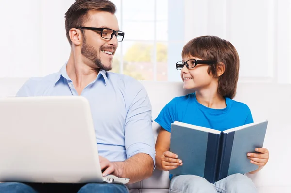 Vader werken aan laptop en zoon leesboek — Stockfoto