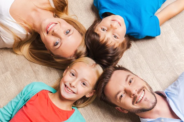 Happy family of four lying on the floor — Stok Foto