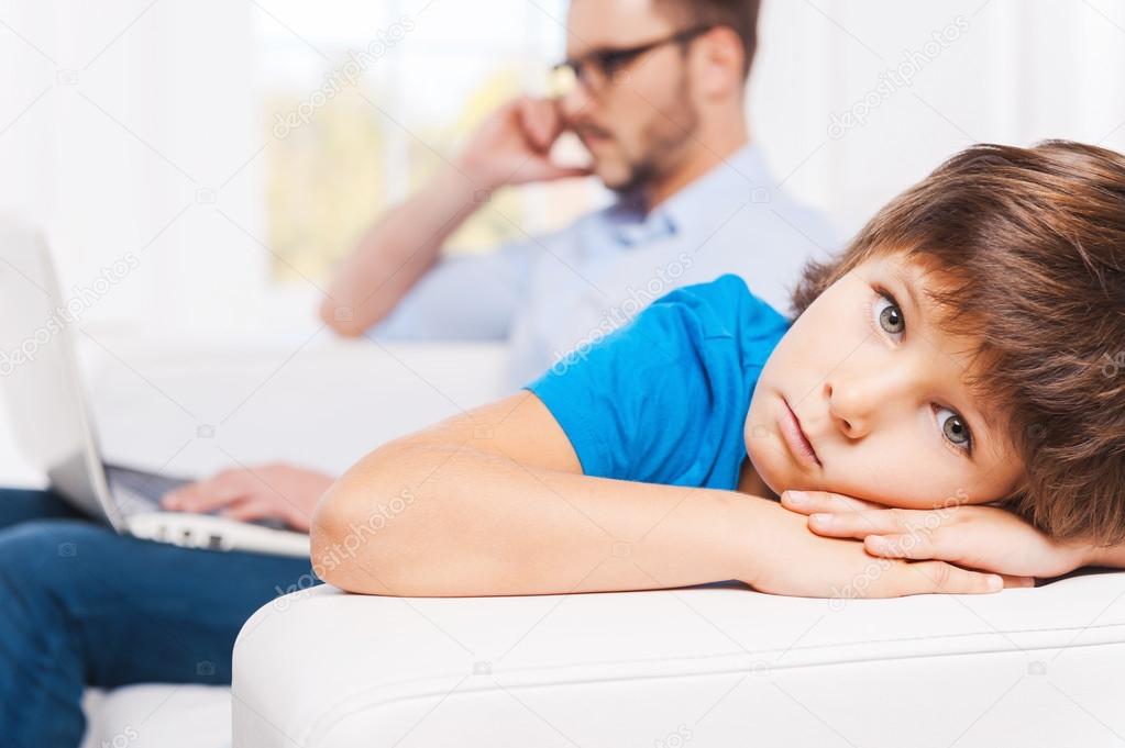 Man working on laptop  with his upset son