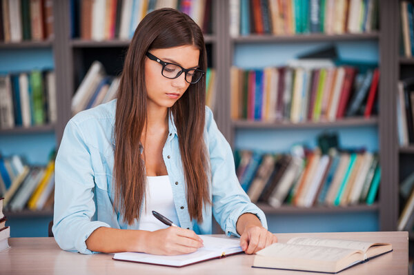 Young woman writing in her note pad