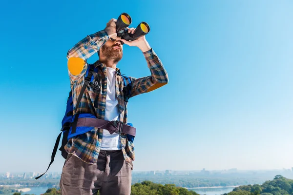 Muž nošení batohu a při pohledu dalekohledem — Stock fotografie