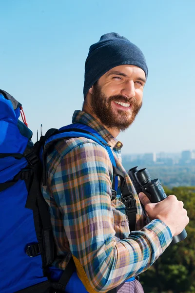 Man carrying backpack and holding binoculars — Stock Photo, Image