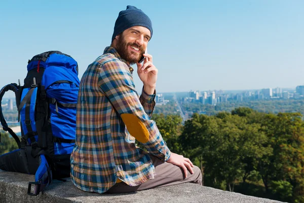 Hombre sentado cerca de la mochila y hablando por teléfono — Foto de Stock