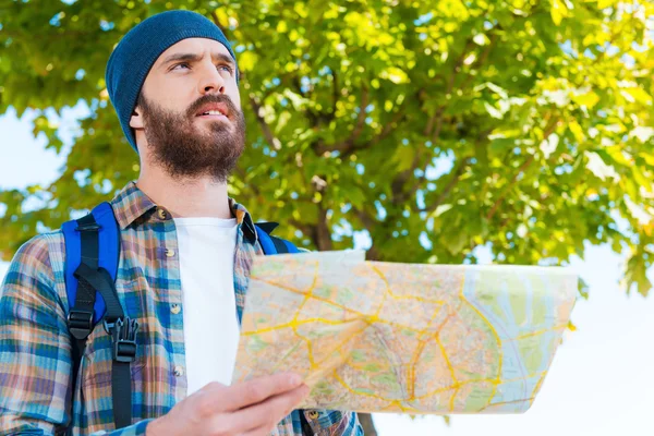 Hombre llevando mochila y sosteniendo mapa — Foto de Stock