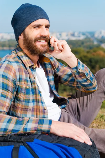 Man sitting near backpack and speaking the telephone — Stock Photo, Image