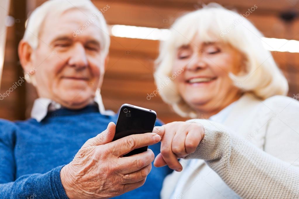 Happy senior couple looking at mobile phone