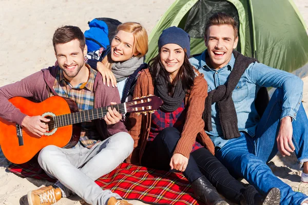 Счастливые люди сидят рядом с палаткой с гитарой — стоковое фото