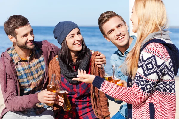 Vrienden praten en drinken bier op het strand — Stockfoto