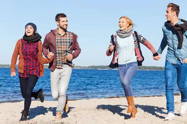 Happy young couples running by the beach — Stock Photo, Image