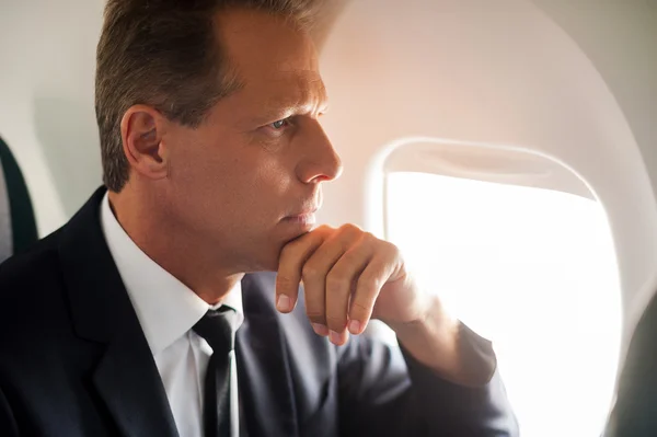 Empresário olhando através da janela do avião — Fotografia de Stock