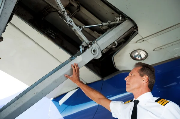 Piloto en uniforme examinando ala de avión —  Fotos de Stock