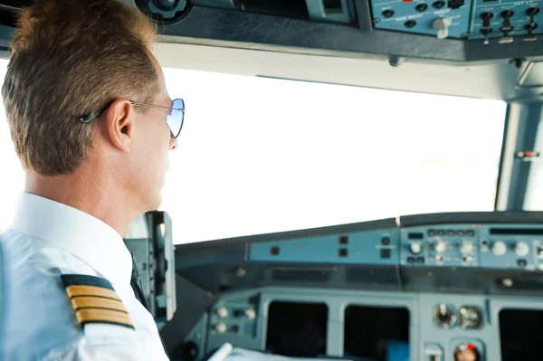 Confident male pilot sitting in airplane cockpit — Stock Photo, Image