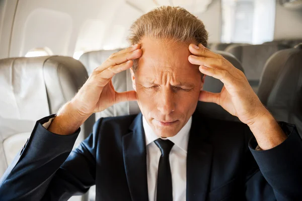 Uomo d'affari toccare la testa con le mani in aereo — Foto Stock