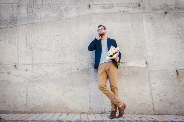 Man holding bouquet of roses and talking on mobile phone — Stock Photo, Image