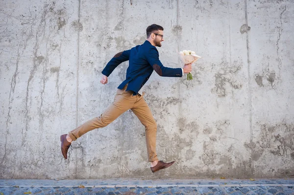 Homem segurando buquê de flores enquanto corre — Fotografia de Stock