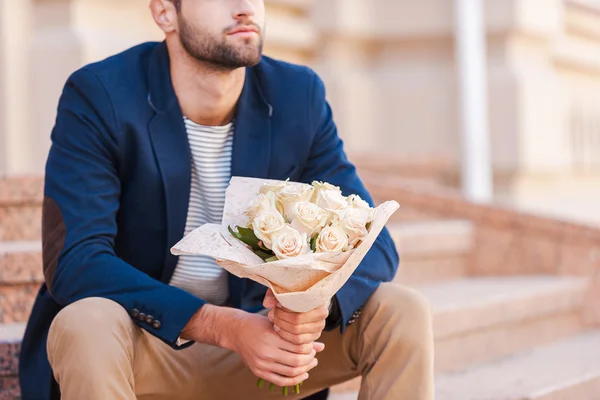 Young man in smart jacket holding bouquet