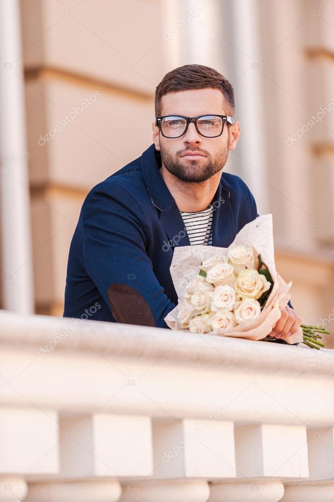Man in smart jacket holding bouquet of flowers