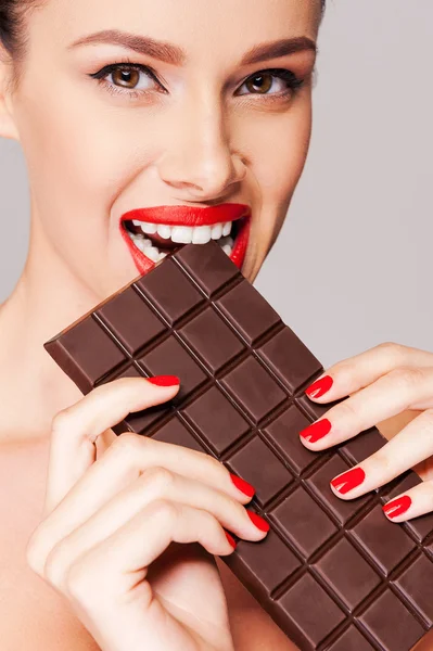 Beautiful woman with red lips biting chocolate bar — Stock Photo, Image