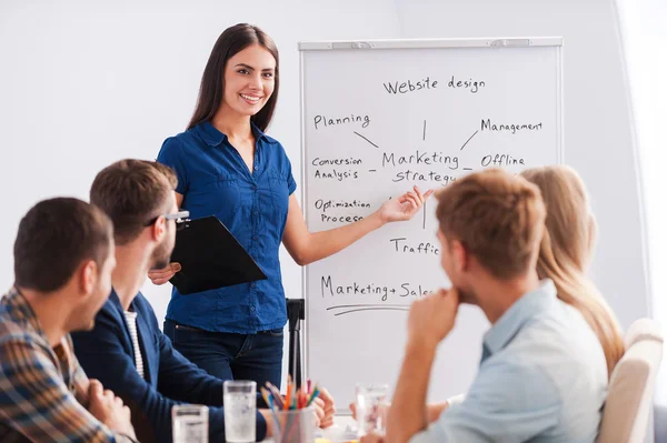 Mulher de pé perto whiteboard e apontando-o — Fotografia de Stock