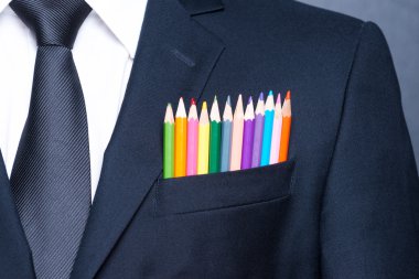 Multicolored businessman.  Close-up of a pocket of businessman with colorful pencils while standing against blackboard clipart