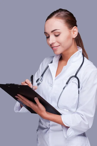 Female doctor writing in clipboard — Stock Photo, Image