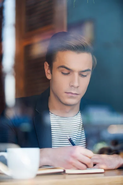 Hombre escribiendo algo en bloc de notas — Foto de Stock