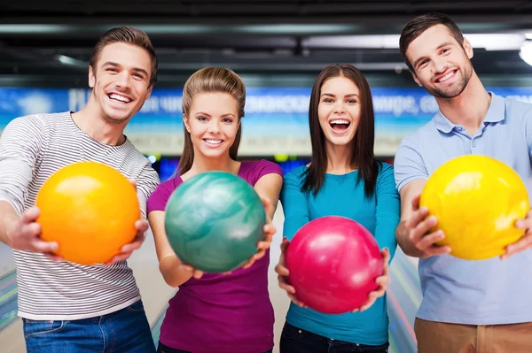 Freunde strecken Bowlingbälle aus — Stockfoto