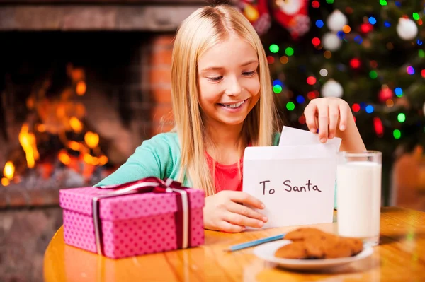 Kleines Mädchen steckt Brief an Weihnachtsmann in den Umschlag — Stockfoto