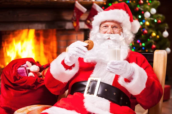 Santa Claus drží sklo s mlékem a cookie — Stock fotografie